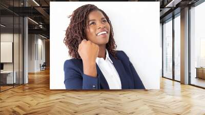 Happy joyful female employee making winner gesture, looking up, smiling, laughing. Young African American business woman standing isolated over white background. Win or success concept Wall mural