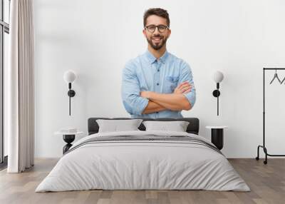 Happy laughing guy posing with arms folded. Handsome young man in casual shirt and glasses standing isolated over white background. Male portrait concept Wall mural