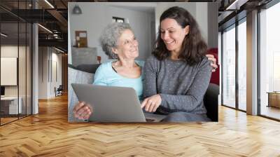 Happy senior woman and her daughter using laptop computer Wall mural