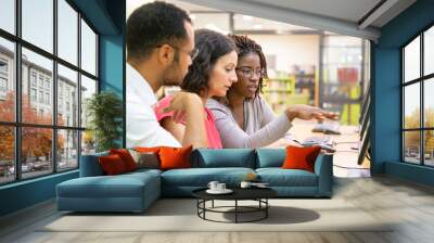 Instructor explaining corporate software specific to trainees in computer class. Man and women sitting at table, using desktop, pointing at monitor and talking. Training concept Wall mural