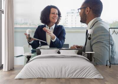 Joyful corporate trainer telling newcomer about work in company. Happy business woman holding tablet and talking to male colleague at meeting table. Newcomer concept Wall mural