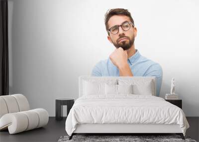 Pensive male customer looking away at copy space, touching chin, thinking. Handsome young man in casual shirt and glasses standing isolated over white background. Advertising concept Wall mural