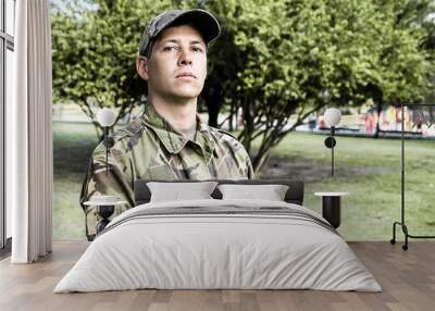 Portrait of guard in park. Serious man in military camouflage uniform standing in park, looking at camera. Medium shot. Military man or guard concept Wall mural