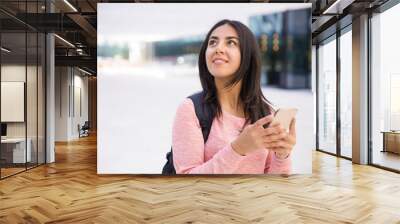 Positive dreamy girl using gadget and looking up Wall mural