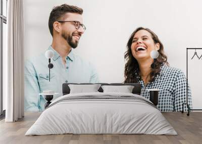 Positive funny guy making his girlfriend laugh. Young woman in casual and man in glasses in glasses posing isolated over white background. Having fun together concept Wall mural