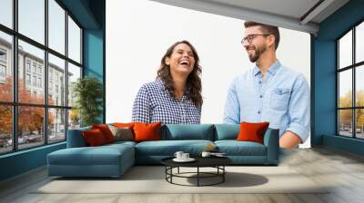 Positive funny guy making his girlfriend laugh. Young woman in casual and man in glasses in glasses posing isolated over white background. Having fun together concept Wall mural