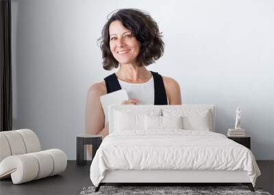 Positive smiling woman with tablet posing over white background. Happy middle aged woman holding digital device and smiling at camera. Computer technology concept Wall mural