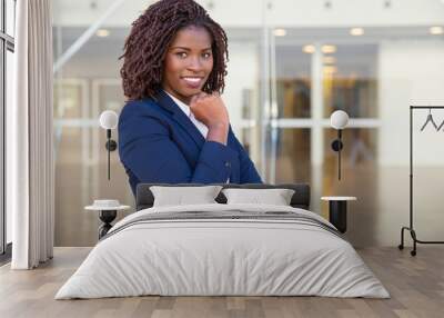 Smiling confident businesswoman posing near office building. Young African American business woman standing outside, looking at camera, smiling. Female business portrait concept Wall mural