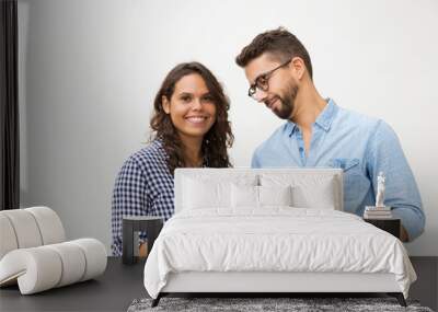 Smiling curious guy in glasses looking at girlfriend cellphone screen. Young woman in casual and man in glasses in glasses posing isolated over white background. Communication concept Wall mural