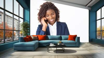 Smiling positive manager talking on cellphone, getting good news. Young African American business woman standing isolated over white background. Phone call concept Wall mural