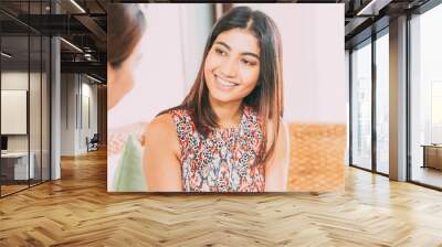 Smiling young woman talking to friend indoor Wall mural