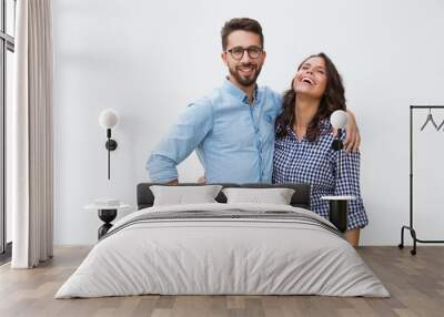 Sweet happy couple hugging each other and laughing. Young woman in casual and man in glasses in glasses posing isolated over white background. Love and friendship concept Wall mural