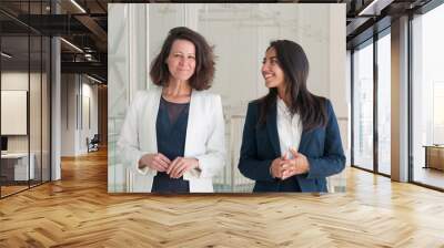 Two joyful beautiful business women in office hall Wall mural