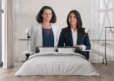 Two smiling business woman posing at camera in office hall Wall mural