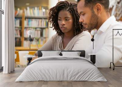 Two thoughtful people working with laptop at public library. Concentrated African American man and woman using laptops. Technology concept Wall mural