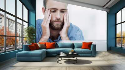 Young bearded Caucasian manager sitting in office in stress and having trouble while working at laptop Wall mural