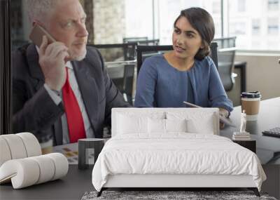 young business expert annoyed with phone talk of her colleague during meeting. mid adult man in form Wall mural