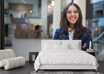 Young businesswoman smiling at camera. Portrait of cheerful Hispanic businesswoman in formal wear standing with crossed arms and looking at camera. Business concept Wall mural