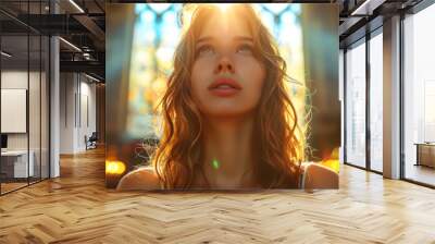 A young woman kneels in a pew in a church, her hands clasped in prayer Wall mural