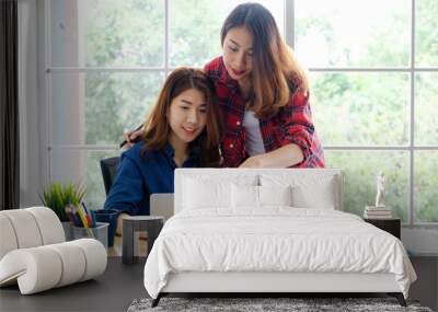  Two young asian women working with laptop computer at home office with happy emotion, working from home, small business, office casual lifestyle concept Wall mural