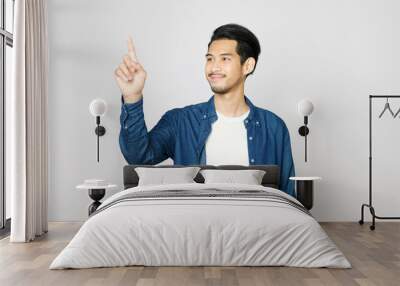 Young asian man handpoint smiling while standing over isolated grey background Wall mural