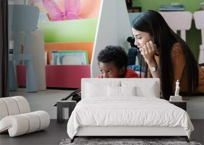 Young asian woman teacher and African boy in kindergarten classroom, preschool education concept Wall mural