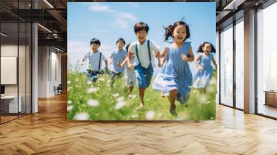 Group of happy little asian kids running on green summer field with Blue sky background. Wall mural