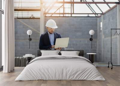 An Asia man engineer is working manager on a project under construction for a house.A handsome man  with black skin was smiling confidently. Wear personal protective equipment,PPE. Wall mural