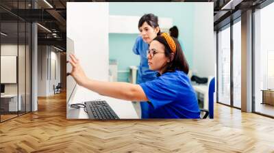 Two nurses using a computer in a x-ray room Wall mural