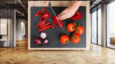 Top down view on cutting board with hands slicing vegetables Wall mural