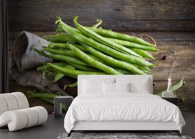 A close-up of vibrant green beans in a natural wooden bowl, showcasing freshness and organic produce. Wall mural