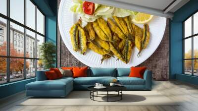 anchovies battered with flour and fried with lettuce and tomato, wooden background Wall mural