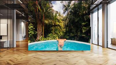 Young woman relaxes by bathing in an infinity pool at a luxurious Costa Rica resort Wall mural