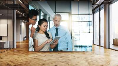 Using technology to take brainstorming to the next level. Shot of a business team using a digital tablet while having an informal meeting. Wall mural