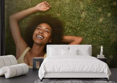 This is the life. Shot of a young woman laughing while relaxing on the grass. Wall mural