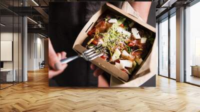 Woman's hand is holding a take away fresh salad in a lunch box. Gourmet conception. Wall mural