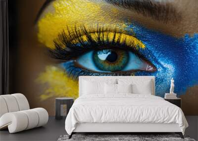 A striking close-up of an eye adorned with bold blue and yellow artistic makeup, emphasizing expression, creativity, and the beauty of unique makeup artistry. Wall mural