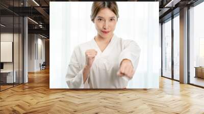 Portrait of woman in Taekwondo clothes show fighting pounch on white background . Wall mural