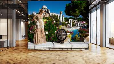 Glamour, stylish elegant woman in long gown feather dress is posing need the pool in luxury hotel. Female model in amazing long dress. Outdoor shoot. Vogue. Couture. Wall mural