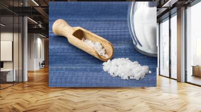 Salt crystals with wooden spoon and glass salt shaker on blue wooden background Wall mural