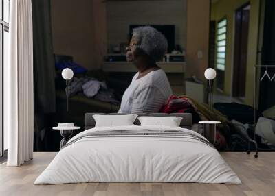 A contemplative older black woman sitting by bedroom looking out window Wall mural