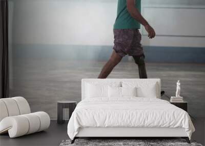 A disabled middle aged man walking with his prosthetic leg indoors Wall mural