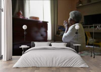 a spiritual older black woman praying to god sitting in bedroom Wall mural