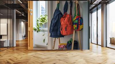 coat rack made of light pine wood, placed in a family home entryway, with children’s coats and colorful backpacks hanging Wall mural