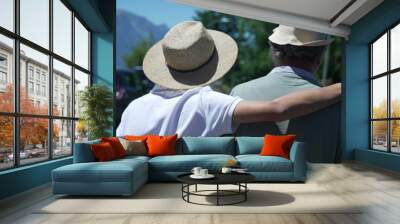 Back of son embracing father with arm around walking outside together wearing Panama Hats during sunny beautiful day Wall mural