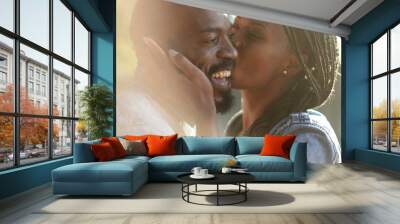 Candid African couple together outside at park. Woman kissing man in cheek outside Wall mural