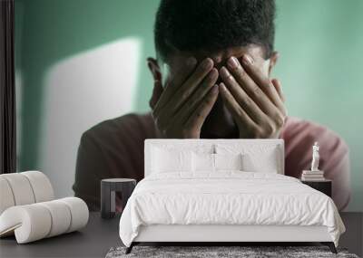 Desperate young man feeling hopeless and despair. A hispanic South American person crying covering face with hand 2 Wall mural