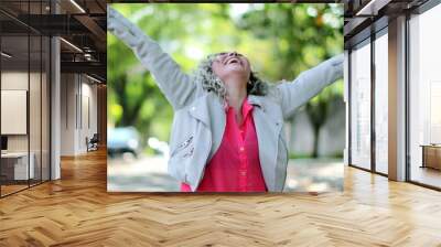 Ecstatic woman jumping with joy celebrating success outside in street Wall mural