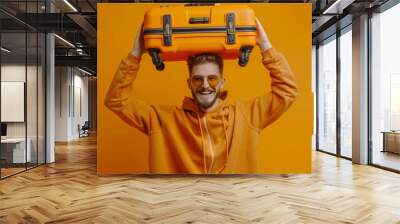 man carrying an orange suitcase on orange background. vacation concept Wall mural