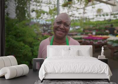 One Happy African American senior woman wearing green apron standing inside Flower Shop looking at camera smiling Wall mural